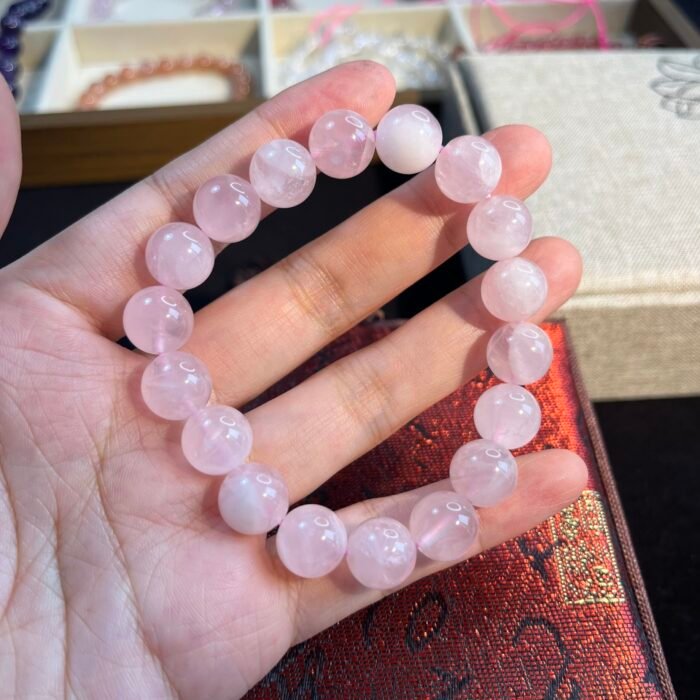 alt="light pink crystal bracelet rose quarts for memen in hand"