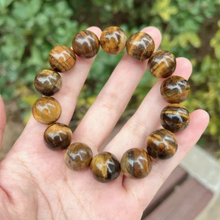 alt="tiger eye stone bracelet for men in hand"