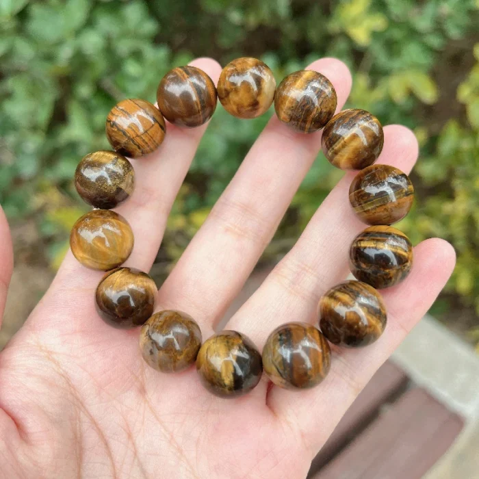 alt="tiger eye stone bracelet for men in hand"