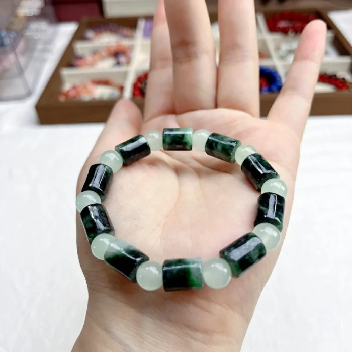 alt="cylinder shaped jade bracelet in hand"