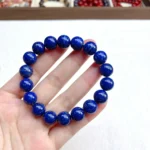 alt="lapis lazuli bracelet and gemstone in hand"