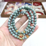 alt="multi loop deep green jade bracelet in hand"