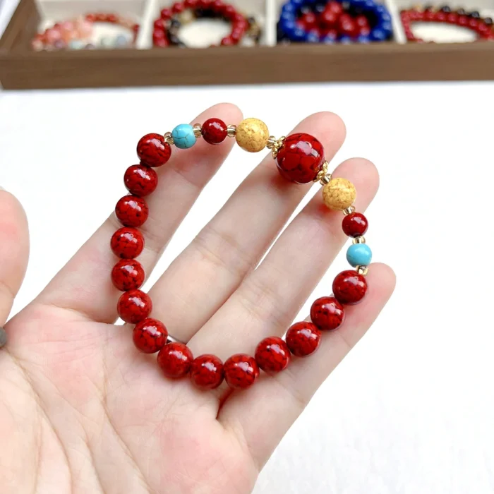 alt="red cennabar bracelet on hand front"