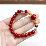 alt="red cinnabar bracelet on hand picture"