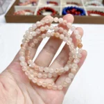 alt="soft orange multi loop crystal bracelet in hand"