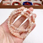 alt="soft orange multi loop crystal bracelet on hand"