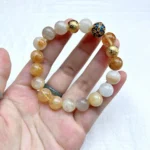 alt="yellow crystal bracelet on hand face"